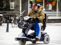 Oudere man met scootmobiel  door de sneeuw Krispijnseweg Dordrecht